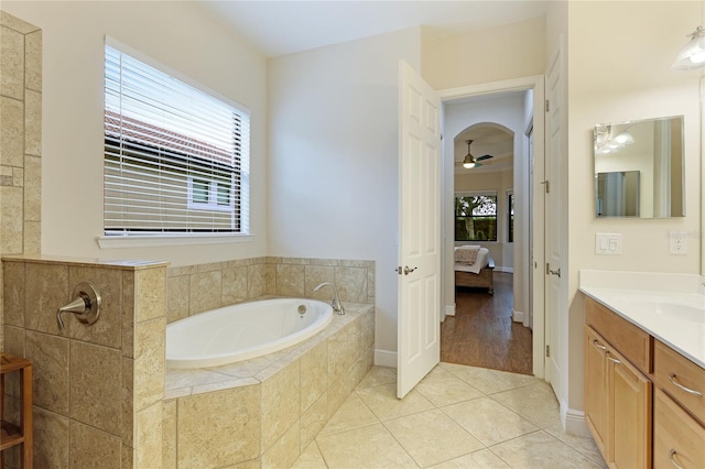 bathroom with tile patterned floors, vanity, ceiling fan, and tiled tub