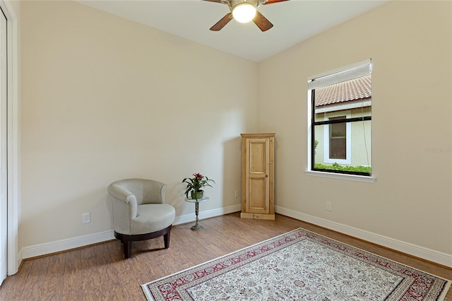 living area with wood-type flooring and ceiling fan