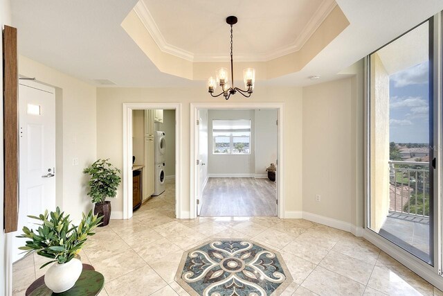 interior space with a tray ceiling, crown molding, and a chandelier