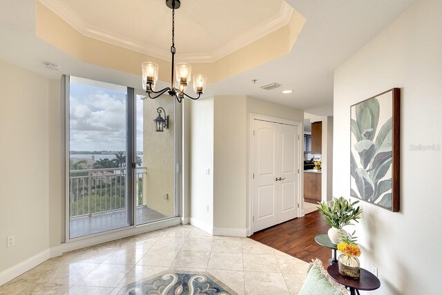 interior space featuring crown molding, a tray ceiling, and a chandelier