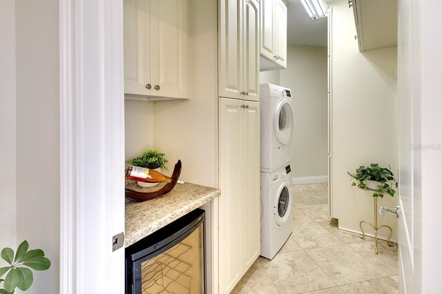 washroom featuring stacked washer / drying machine, light tile patterned floors, and beverage cooler