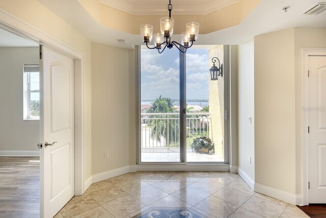 unfurnished dining area with light tile patterned floors, a tray ceiling, crown molding, and a chandelier