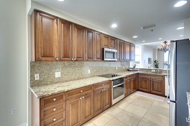 kitchen featuring light stone countertops, backsplash, appliances with stainless steel finishes, and sink