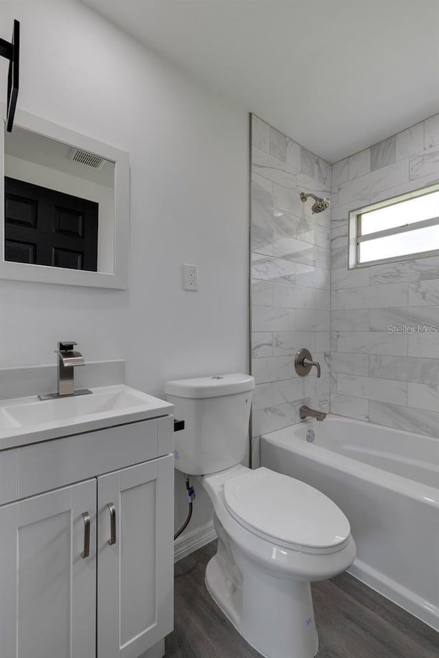 full bathroom featuring vanity, hardwood / wood-style flooring, toilet, and tiled shower / bath