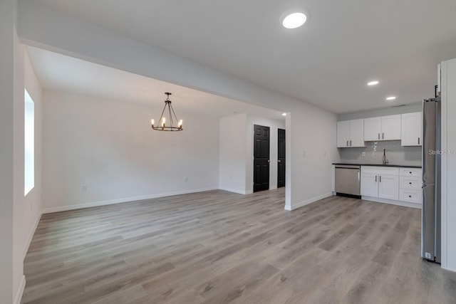 kitchen with white cabinetry, appliances with stainless steel finishes, pendant lighting, light hardwood / wood-style floors, and backsplash