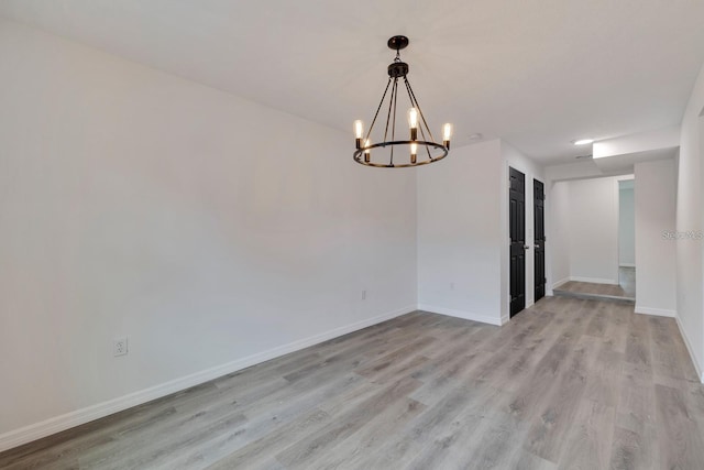 unfurnished room featuring an inviting chandelier and light hardwood / wood-style floors