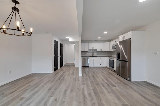 kitchen featuring sink, stainless steel appliances, tasteful backsplash, white cabinets, and decorative light fixtures