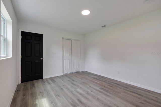 unfurnished bedroom with a closet and light wood-type flooring