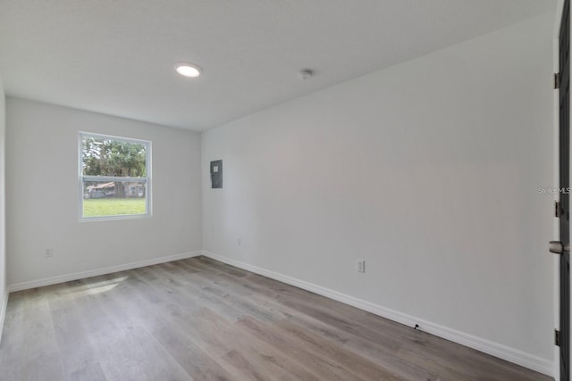 unfurnished room featuring electric panel and light hardwood / wood-style floors