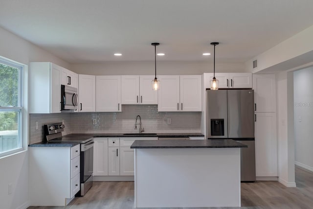 kitchen featuring sink, white cabinetry, decorative light fixtures, appliances with stainless steel finishes, and a kitchen island