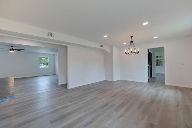 unfurnished room featuring ceiling fan with notable chandelier and light hardwood / wood-style floors