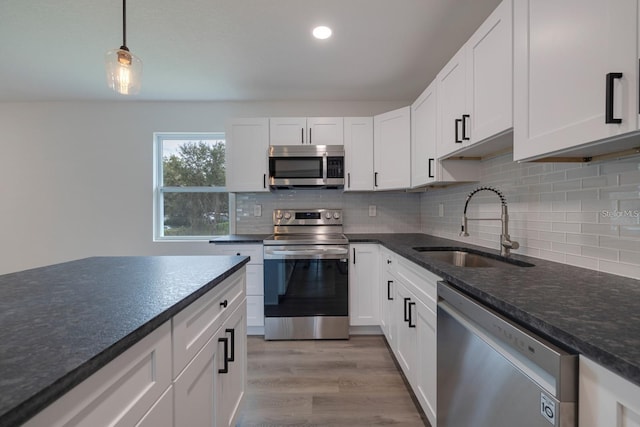 kitchen featuring white cabinetry, stainless steel appliances, sink, and pendant lighting