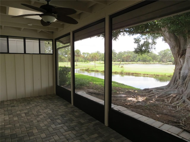 unfurnished sunroom featuring a water view and ceiling fan