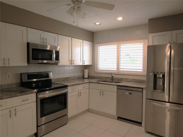 kitchen featuring tasteful backsplash, dark stone counters, stainless steel appliances, sink, and white cabinetry