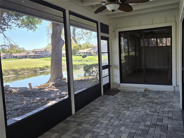 sunroom featuring a residential view, a water view, and a ceiling fan