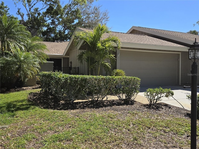 view of front facade featuring concrete driveway, a garage, and roof with shingles