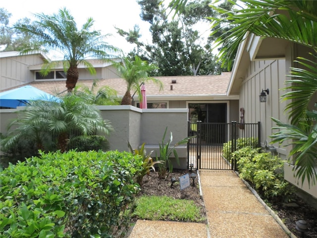 exterior space with stucco siding, fence, a shingled roof, and a gate