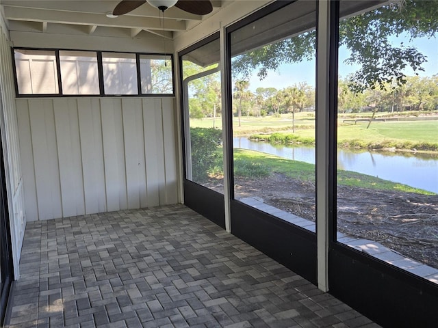 unfurnished sunroom with ceiling fan and a water view