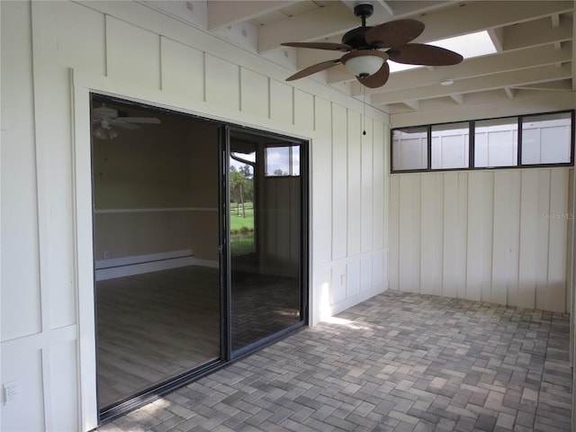 unfurnished sunroom featuring beam ceiling and a ceiling fan