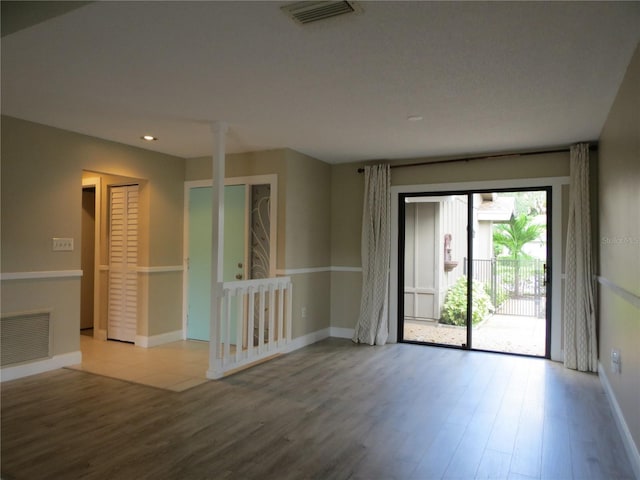 spare room with visible vents, baseboards, and wood finished floors