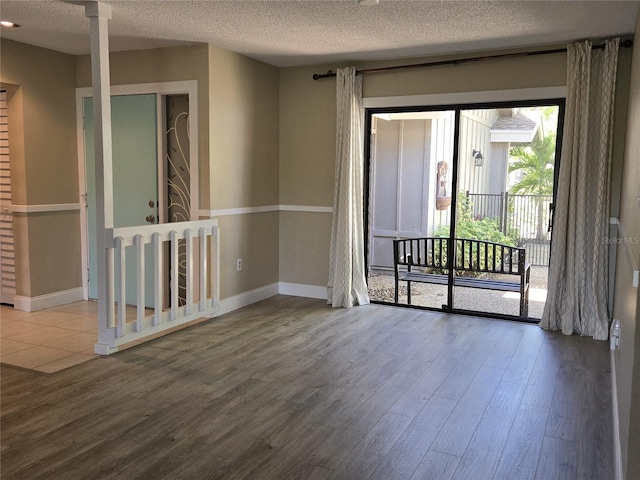 empty room featuring wood finished floors, baseboards, and a textured ceiling