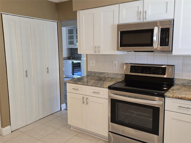 kitchen with stainless steel appliances, wine cooler, backsplash, and white cabinetry