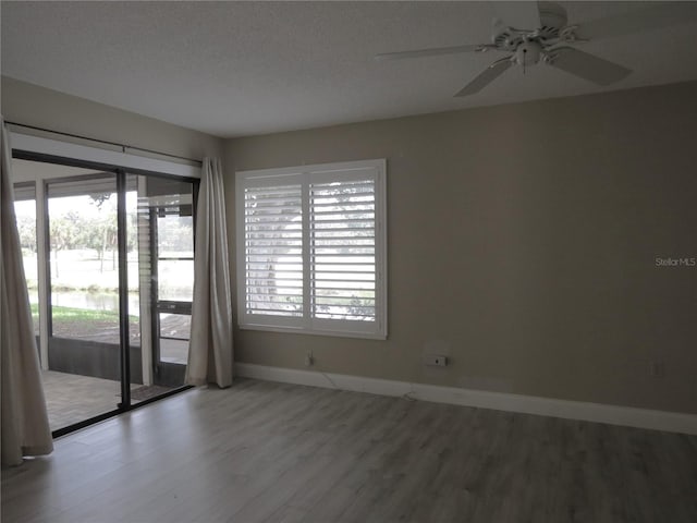 empty room featuring a ceiling fan, wood finished floors, baseboards, and a textured ceiling