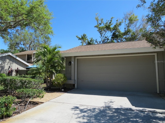 view of front of house featuring driveway, an attached garage, and roof with shingles