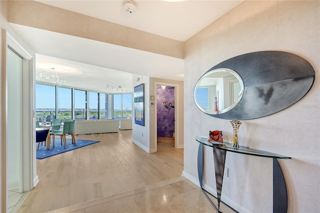 corridor featuring an inviting chandelier and light hardwood / wood-style floors