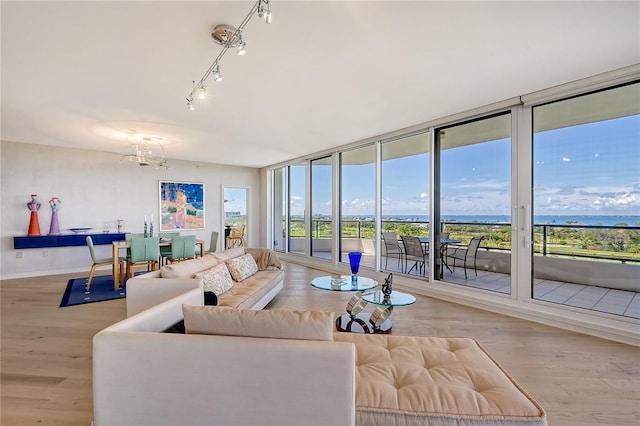 living room with a chandelier, a water view, and light hardwood / wood-style floors