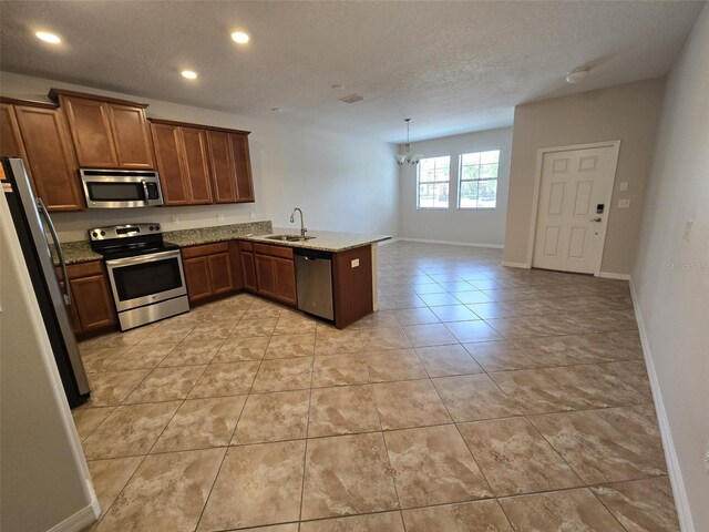 kitchen featuring sink, stainless steel appliances, an inviting chandelier, kitchen peninsula, and light tile patterned floors