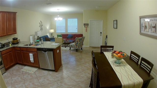 kitchen with an inviting chandelier, stainless steel dishwasher, decorative light fixtures, light tile patterned flooring, and light stone counters