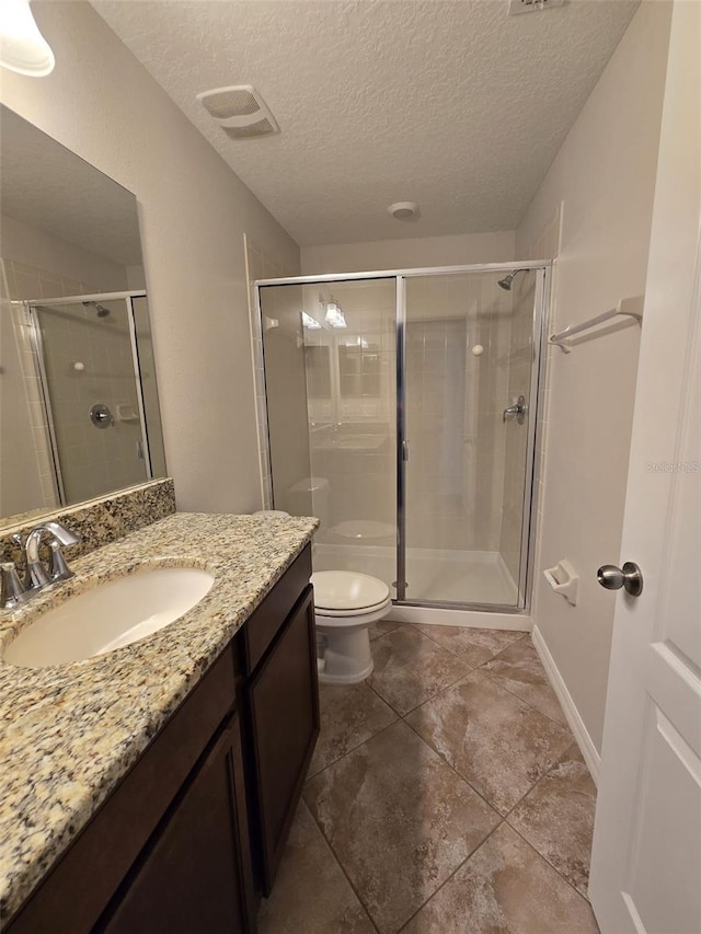 bathroom featuring vanity, a shower with shower door, a textured ceiling, and toilet