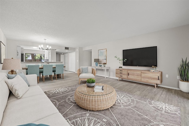 living room featuring hardwood / wood-style flooring, a textured ceiling, and an inviting chandelier