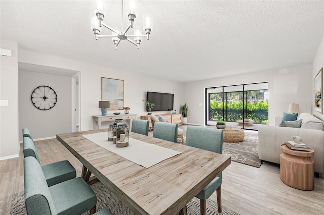 dining space with a notable chandelier, a textured ceiling, and light wood-type flooring