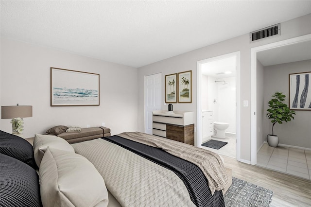 bedroom with connected bathroom and light hardwood / wood-style floors