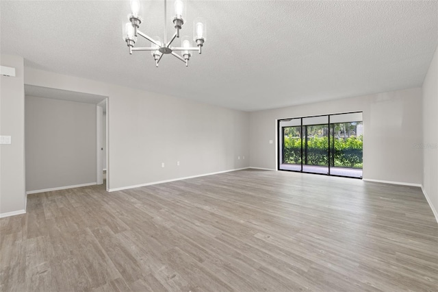 spare room featuring light hardwood / wood-style flooring, a chandelier, and a textured ceiling