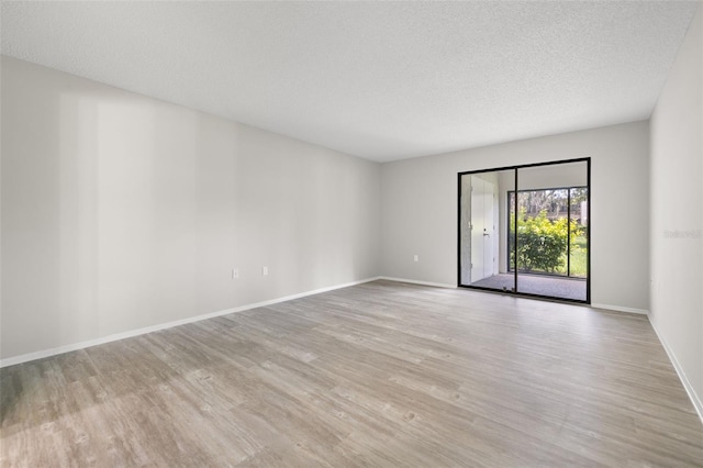 unfurnished room with light wood-type flooring and a textured ceiling