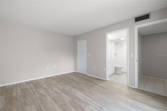 empty room featuring a textured ceiling and light wood-type flooring