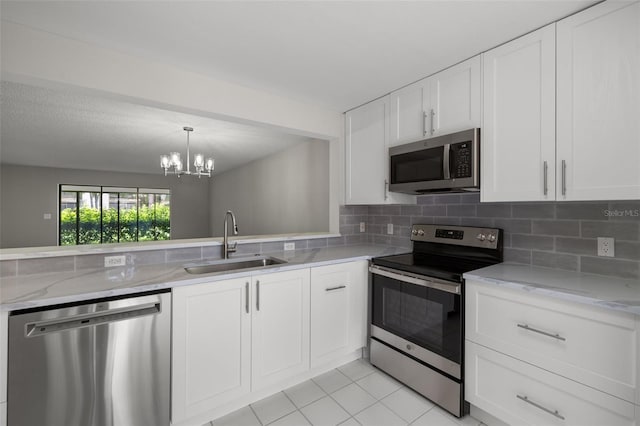 kitchen featuring white cabinets, appliances with stainless steel finishes, a notable chandelier, and sink