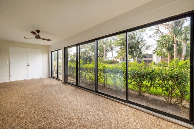 unfurnished sunroom featuring ceiling fan