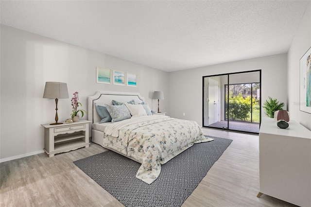 bedroom featuring access to exterior, a textured ceiling, and light hardwood / wood-style flooring