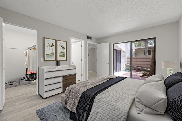 bedroom with light hardwood / wood-style floors, a textured ceiling, and access to outside