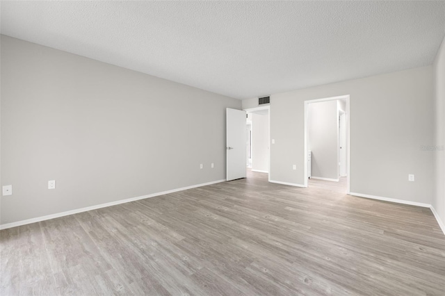 unfurnished room featuring light hardwood / wood-style flooring and a textured ceiling