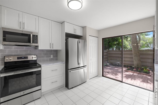 kitchen with white cabinets, light tile patterned floors, backsplash, and appliances with stainless steel finishes