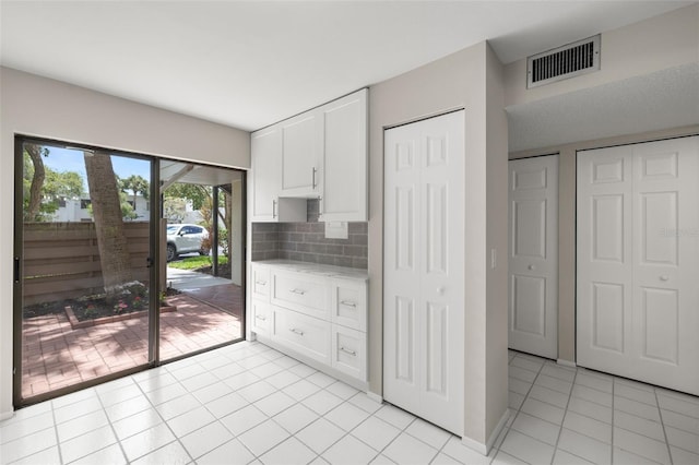 kitchen featuring light tile patterned flooring, white cabinetry, and backsplash