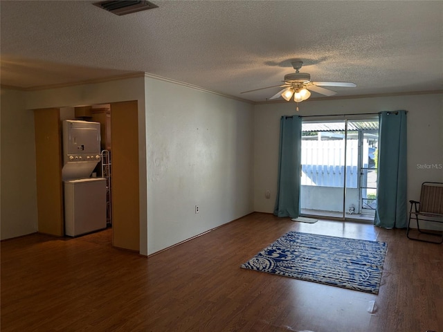 spare room with crown molding, hardwood / wood-style flooring, a textured ceiling, and stacked washer / dryer