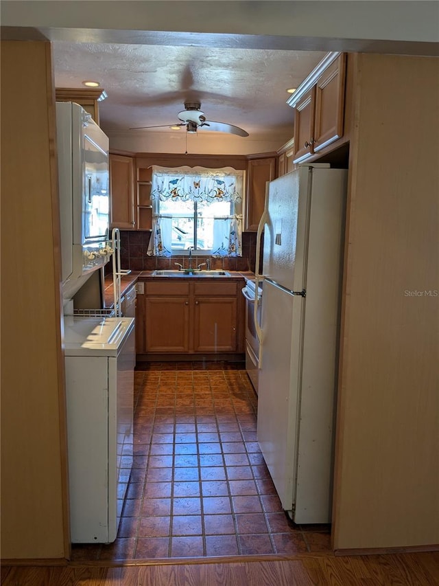 kitchen with white appliances, light brown cabinetry, sink, and decorative backsplash