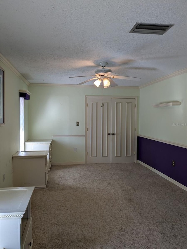 carpeted spare room featuring ceiling fan, ornamental molding, and a textured ceiling