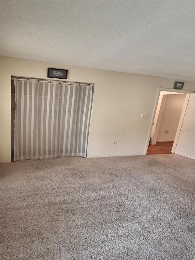 carpeted spare room with a textured ceiling